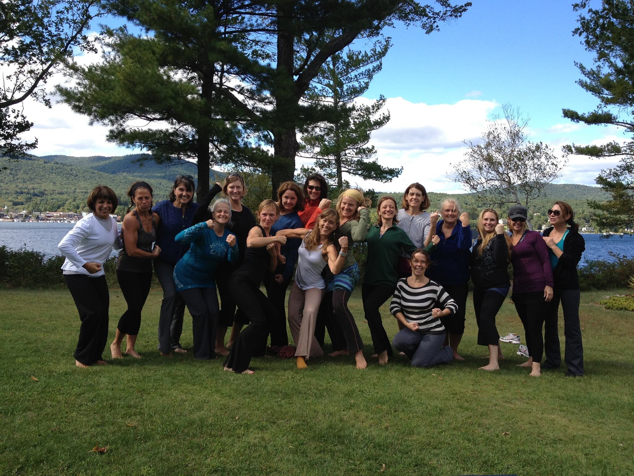 Women’s yoga and wellness retreat group photo at Waiwaka on Lake George, NY with mountains and water in the background.